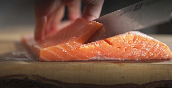 作り方 トラウトサーモンの背と腹の部分に切り口を入れて観音開きにし、観音開きした中に塩、コショウをかける。